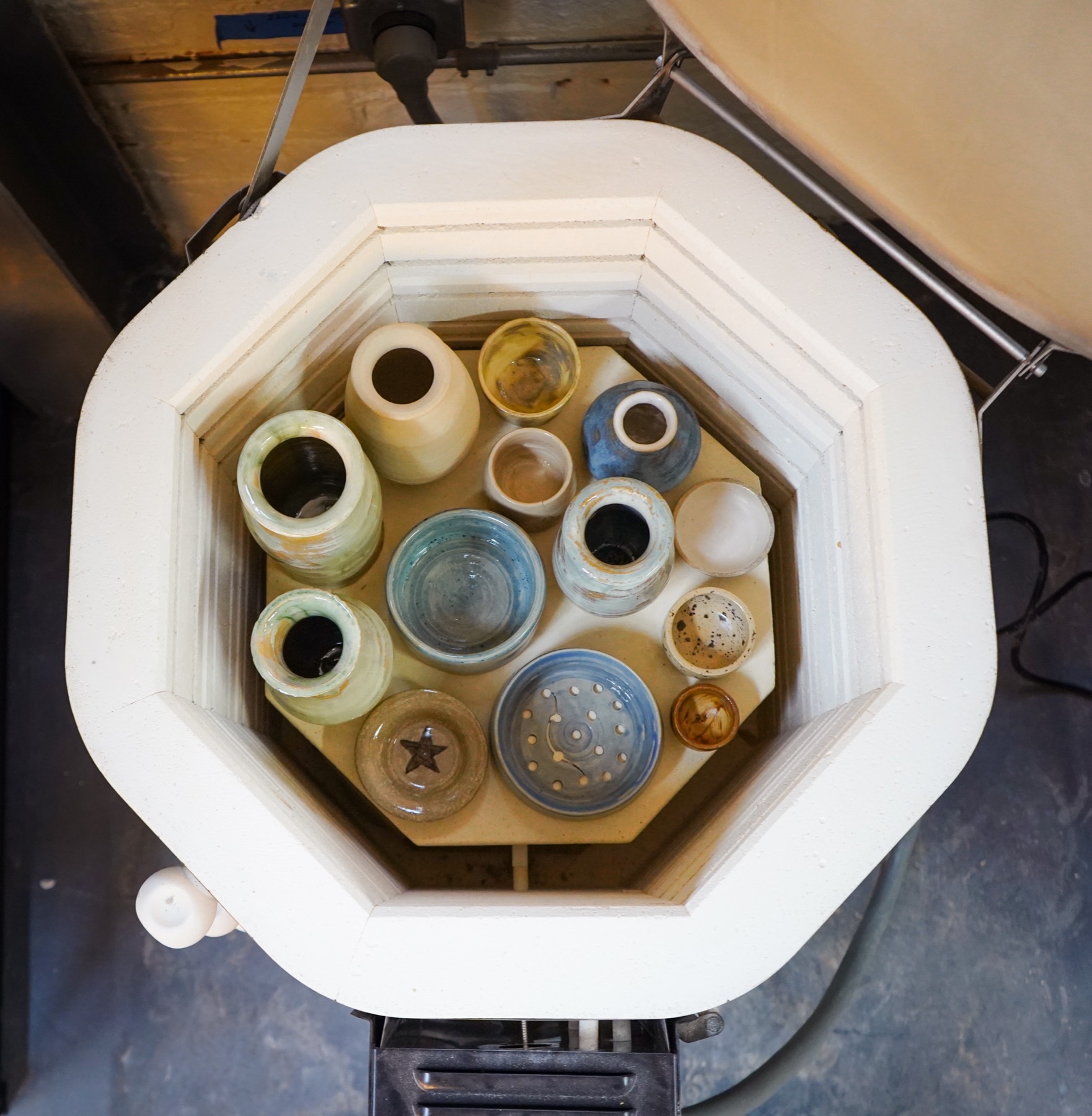 The open kiln seen from above, full of freshly fired glazed jars, bowls, and cups