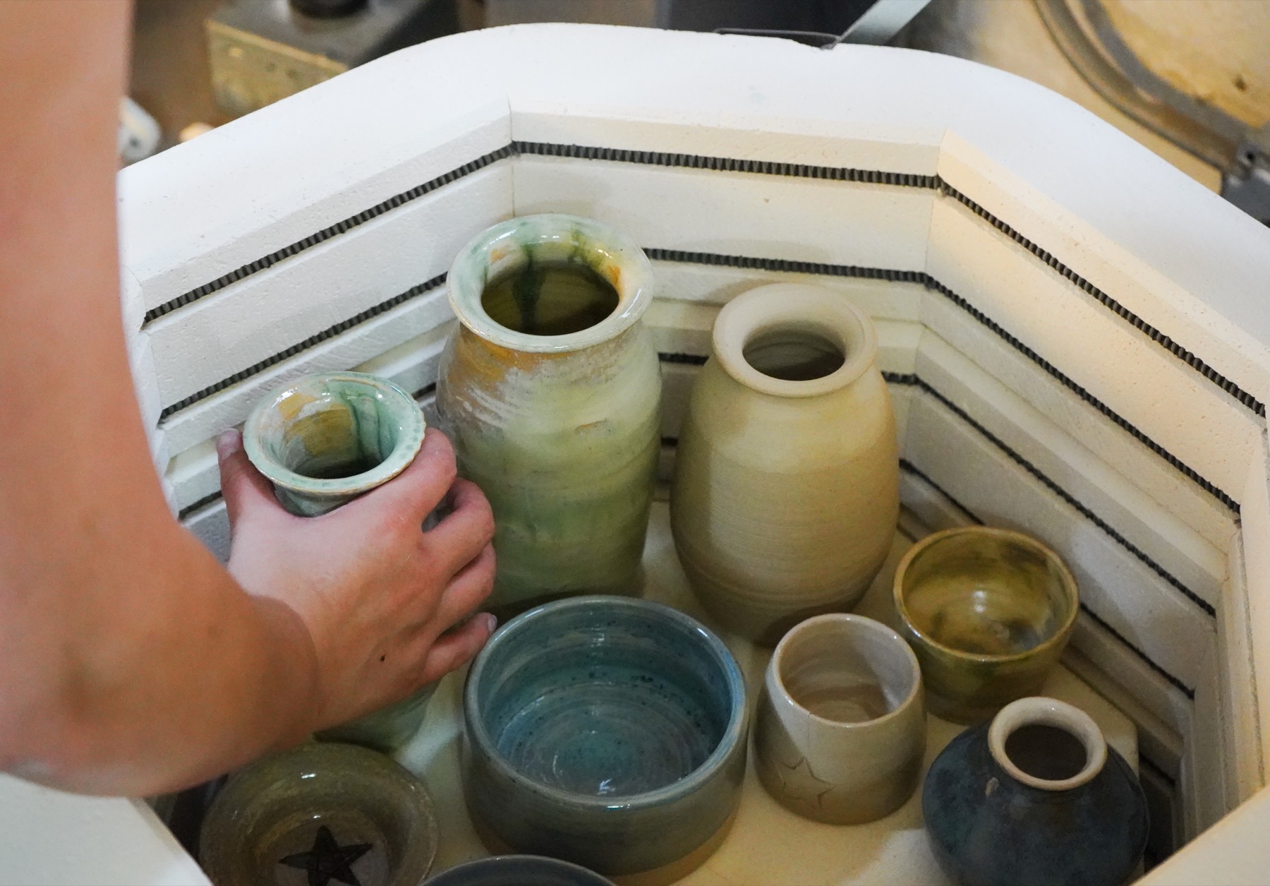 Lifting a glazed cup out of the kiln