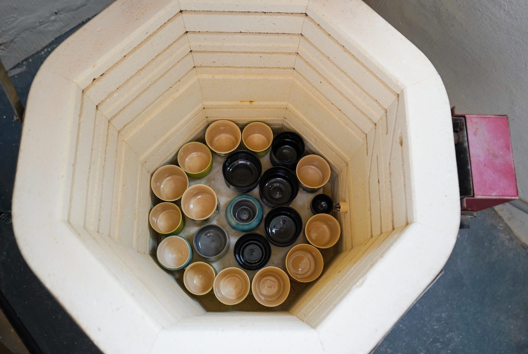 Looking down into a kiln packed with finished glazed cups and bowls