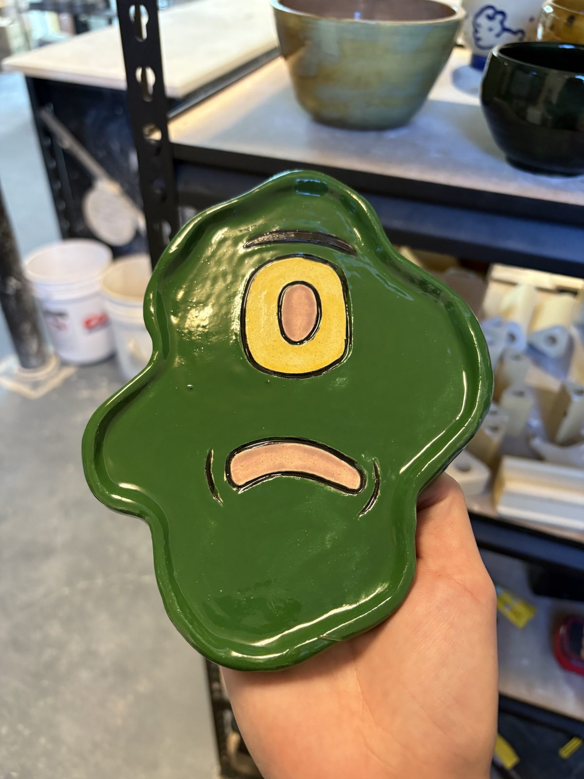 A whimsical green frog-shaped wall dish with googly eyes