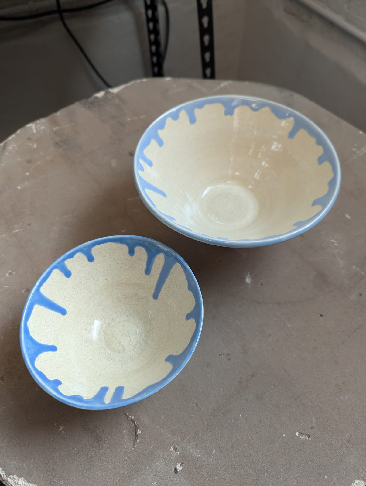 Two small bowls with a blue drip glaze over white