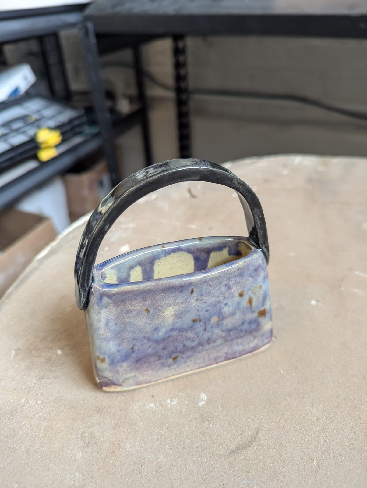 A sculptural ceramic piece shaped like a small handbag