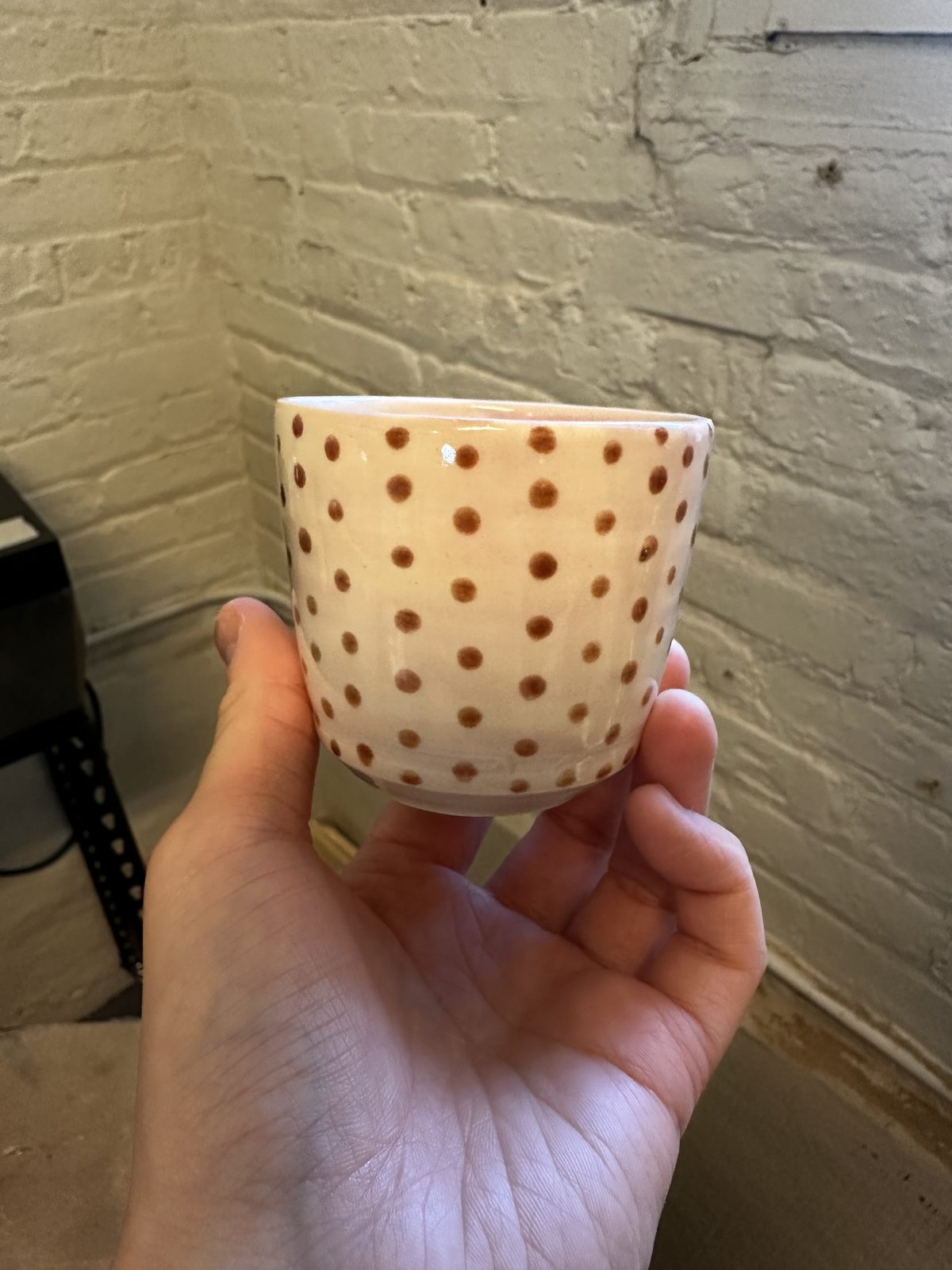 A member holding a small polka-dot mug