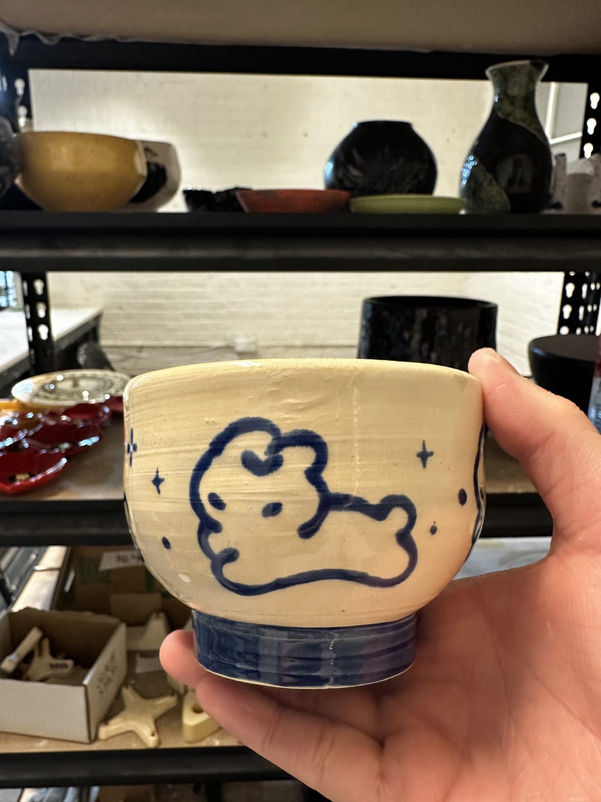 A member holding a bowl hand-painted with a cat illustration in blue and white