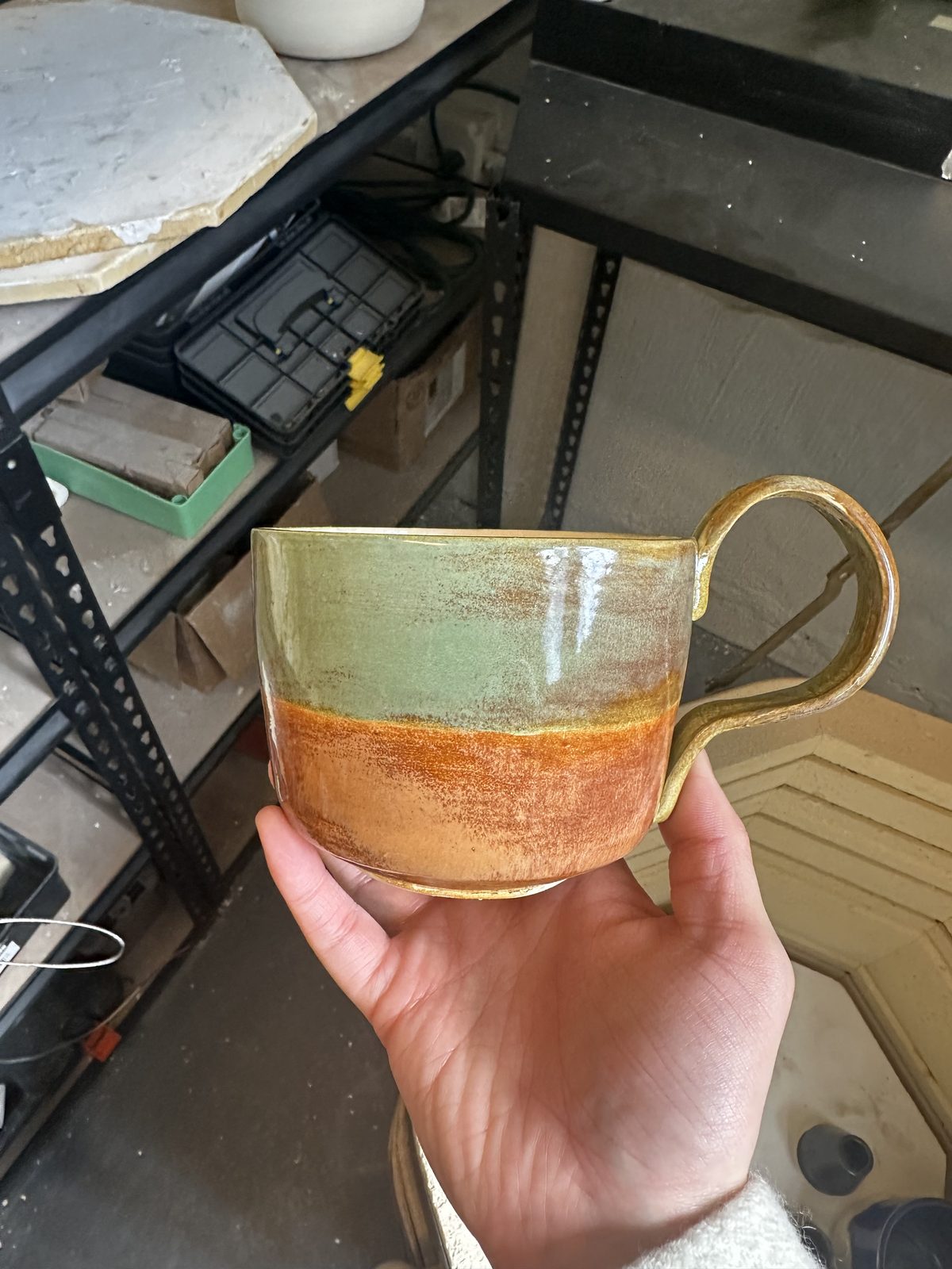 A member holding a mug with an orange-to-white gradient glaze