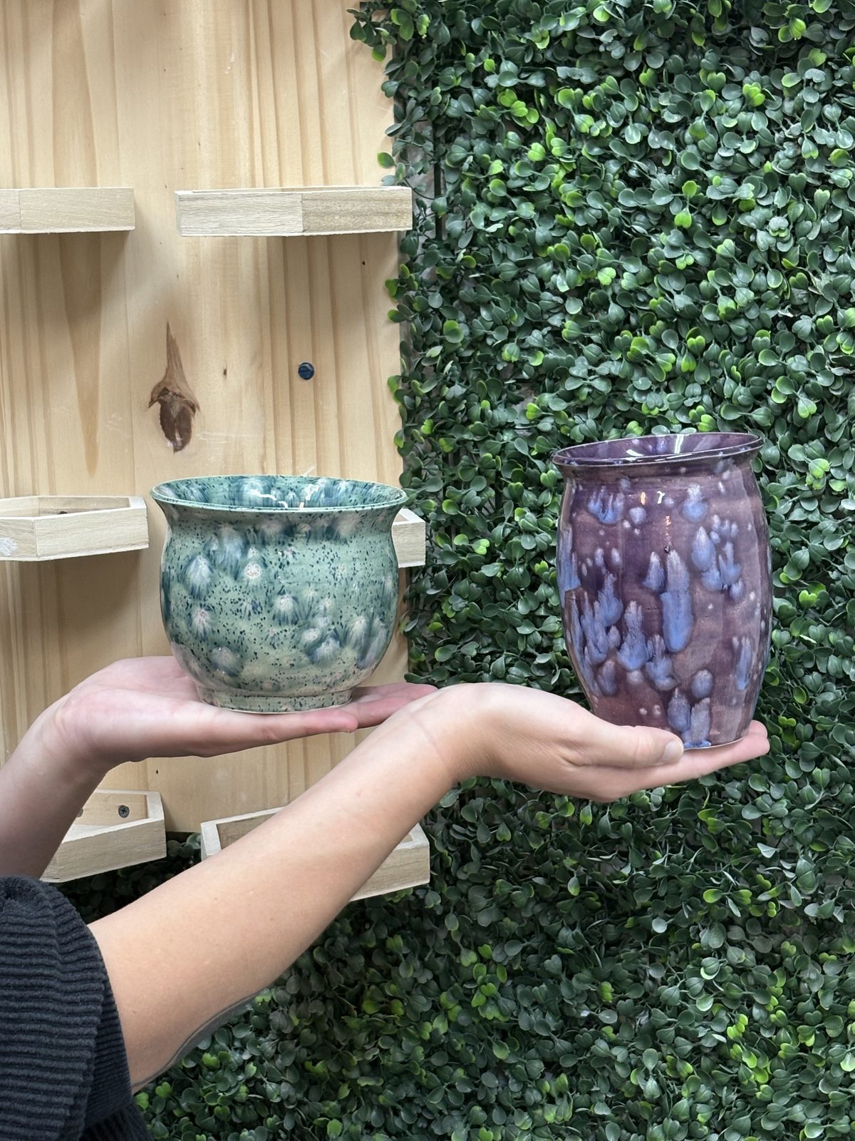 A member holding two mugs, one blue-green and one purple