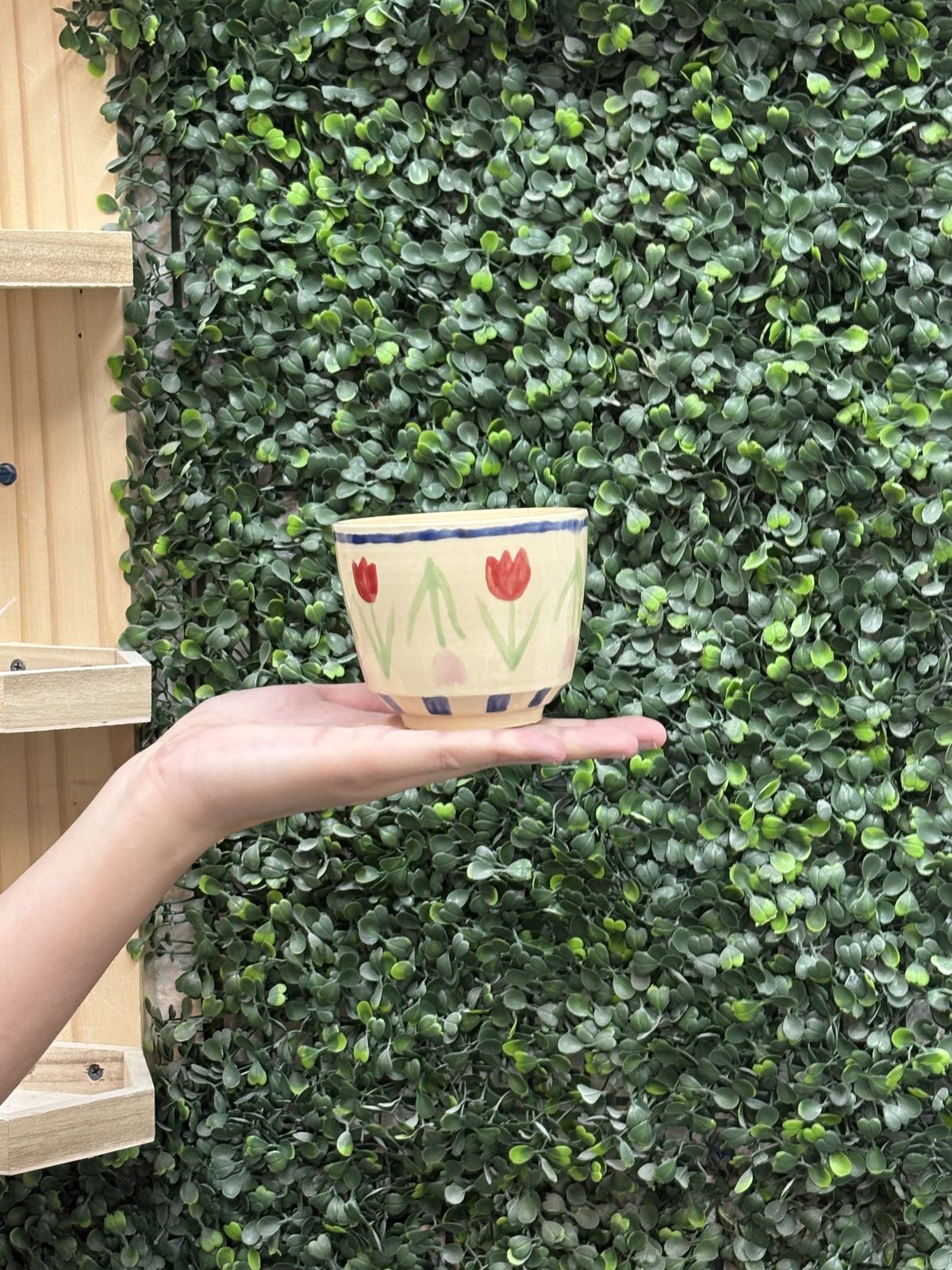 A member holding a mug hand-painted with a tulip design