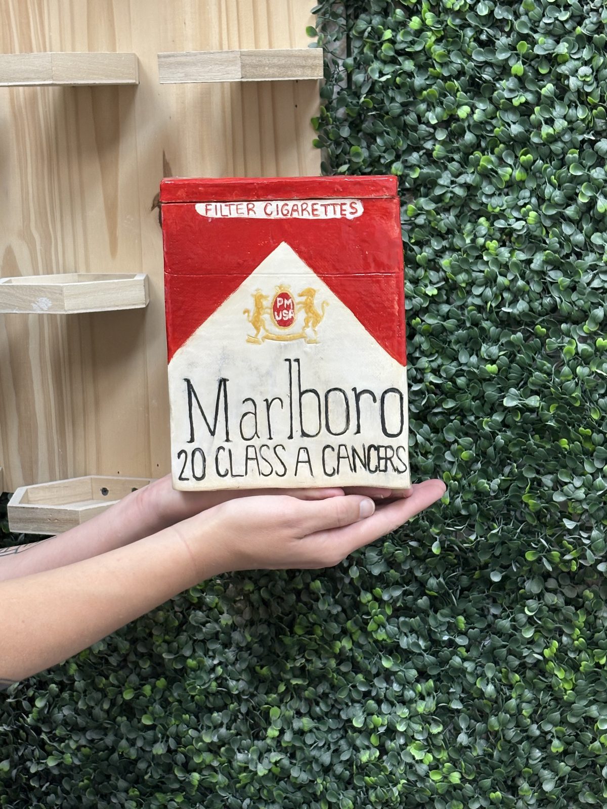 A sculptural ceramic piece shaped and painted like a pack of cigarettes