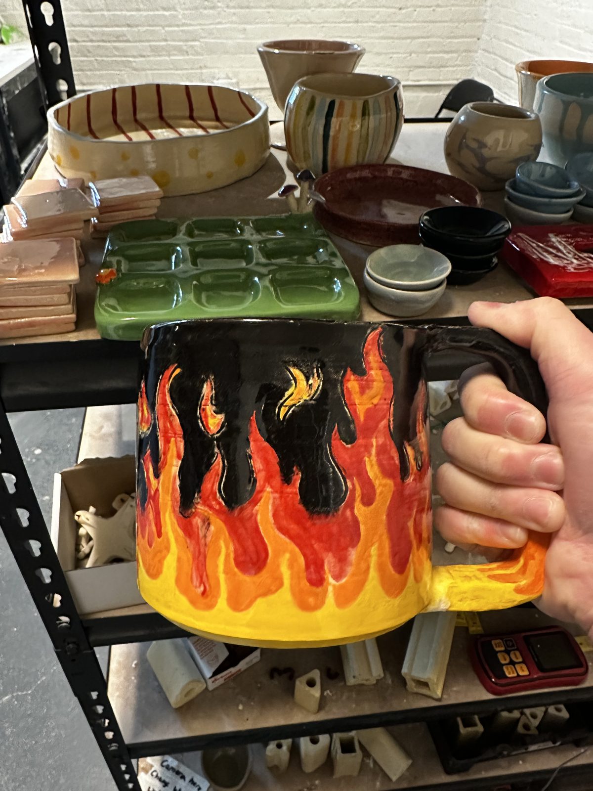 A member holding a mug hand-painted with a flame design