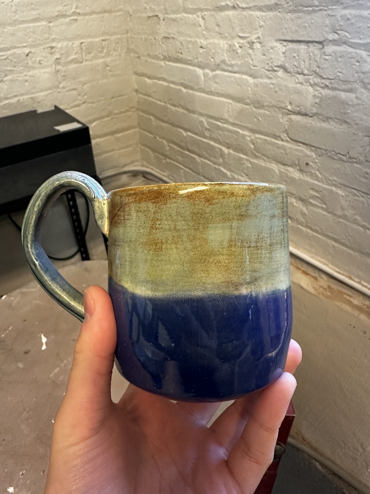 A member holding a mug with a two-tone blue and cream glaze