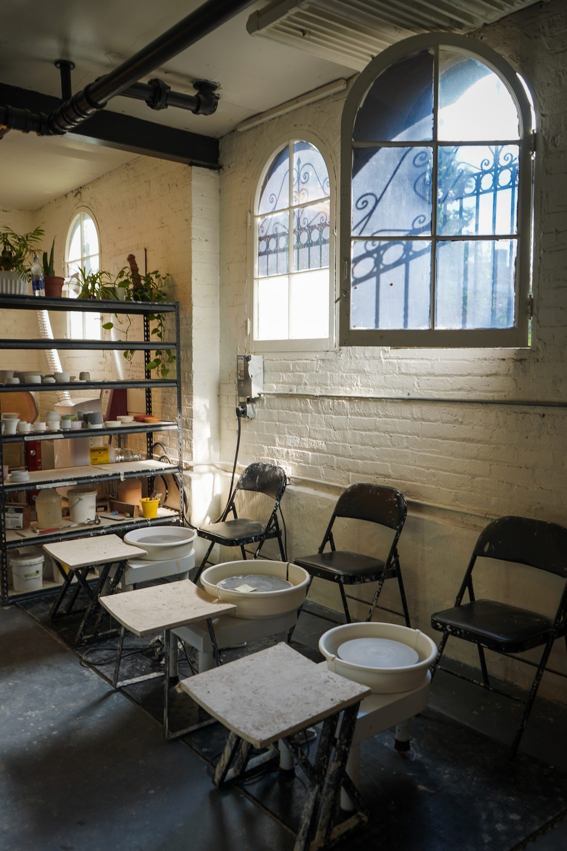Wheel stations lit by the studio's arched, wrought-iron windows against whitewashed brick