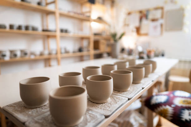 Drying ceramic mugs and bowls on wooden studio shelves